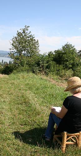 Malerin beim Zeichnen in der Landschaft, im Hintergrund der See